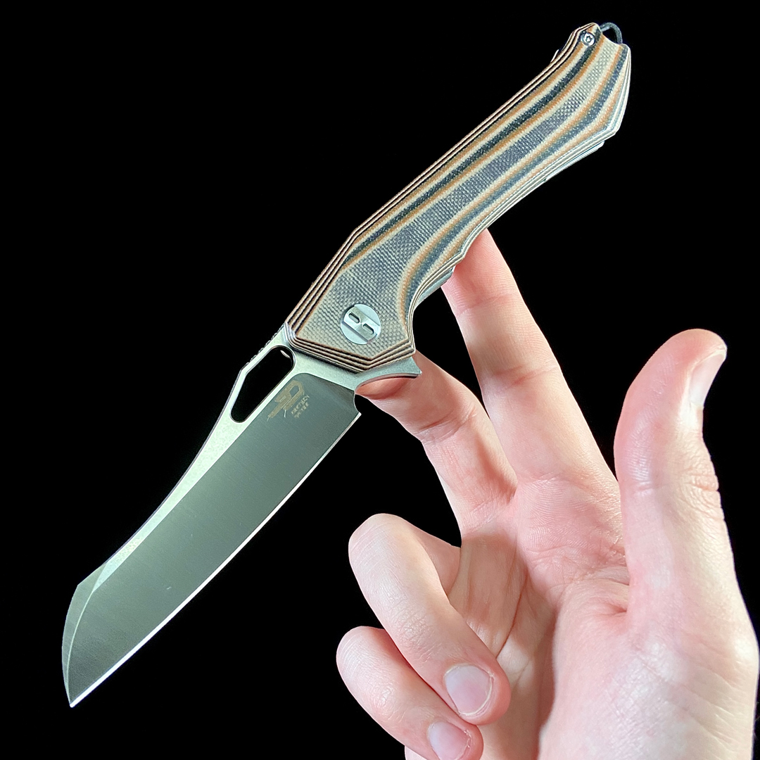 An open Bestech Platypus balanced on two fingers on a black background