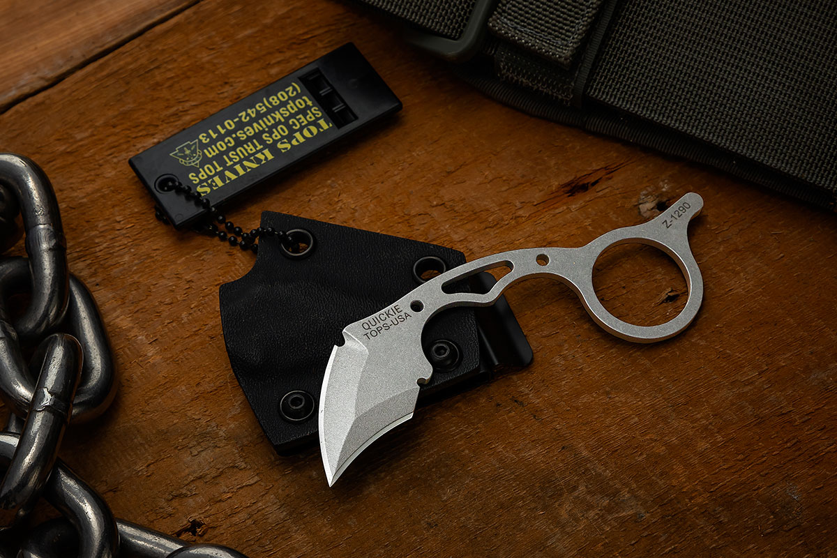 TOPS Quickie 3-Finger Karambit resting on its sheath