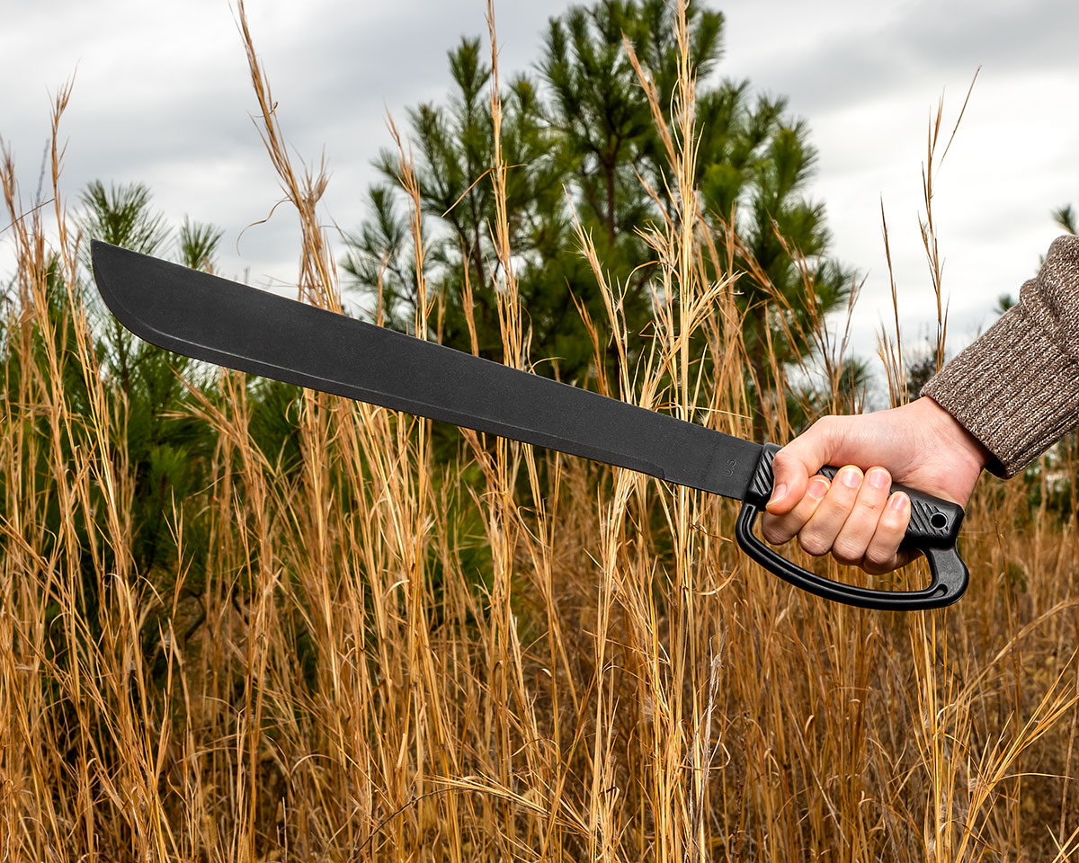 Ontario D-Guard Machete held aloft in front of tall grass