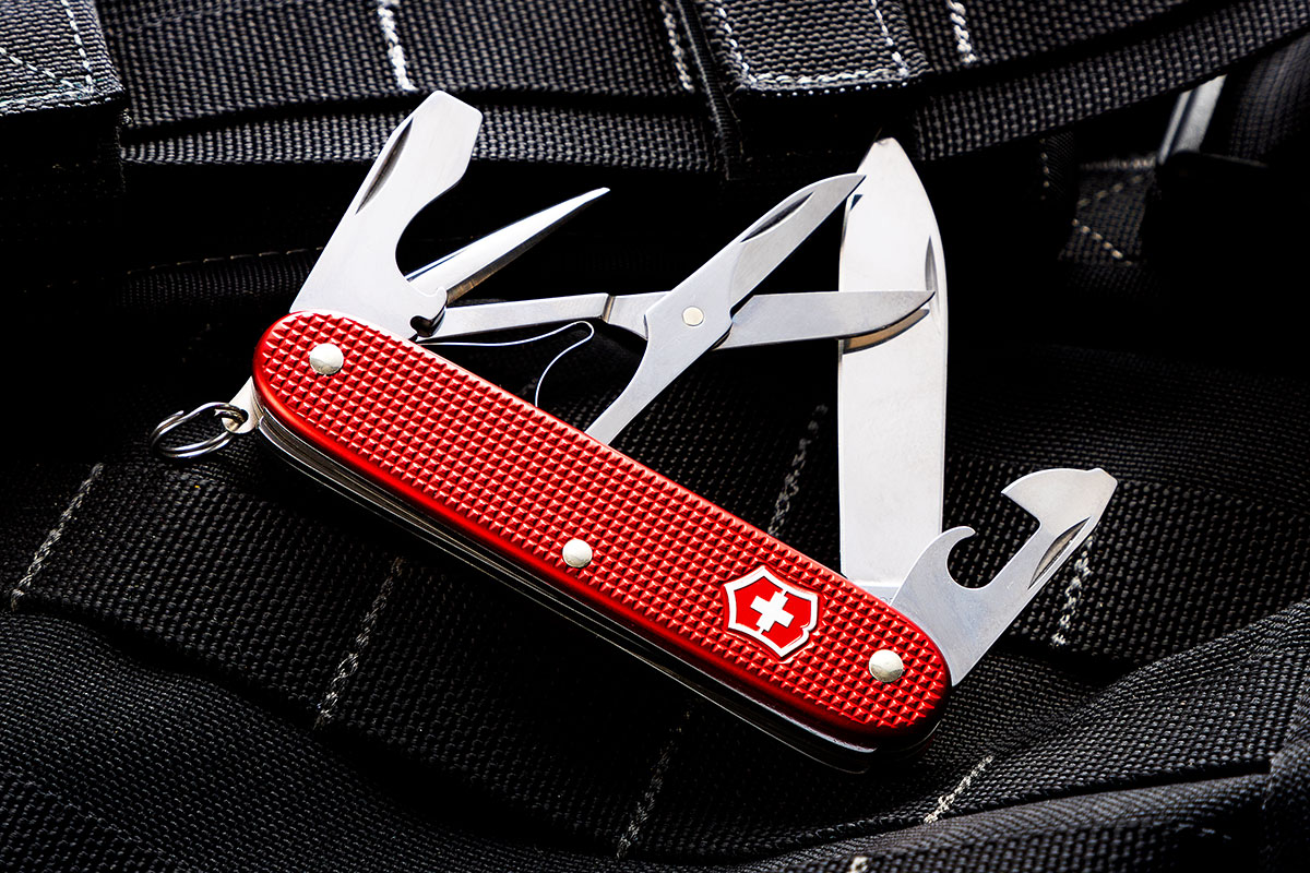 Victorinox Swiss Army Pioneer X Red Alox KnifeCenter Exclusive open on a tactical background