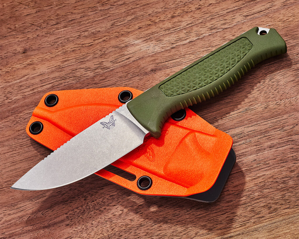 Benchmade Steep Country fixed blade laying on orange sheath, wood background