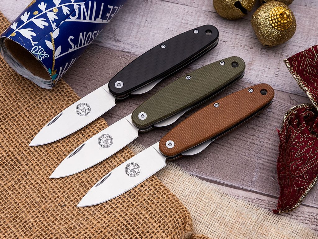 Three ESEE Churp folding knives open on a holiday themed background