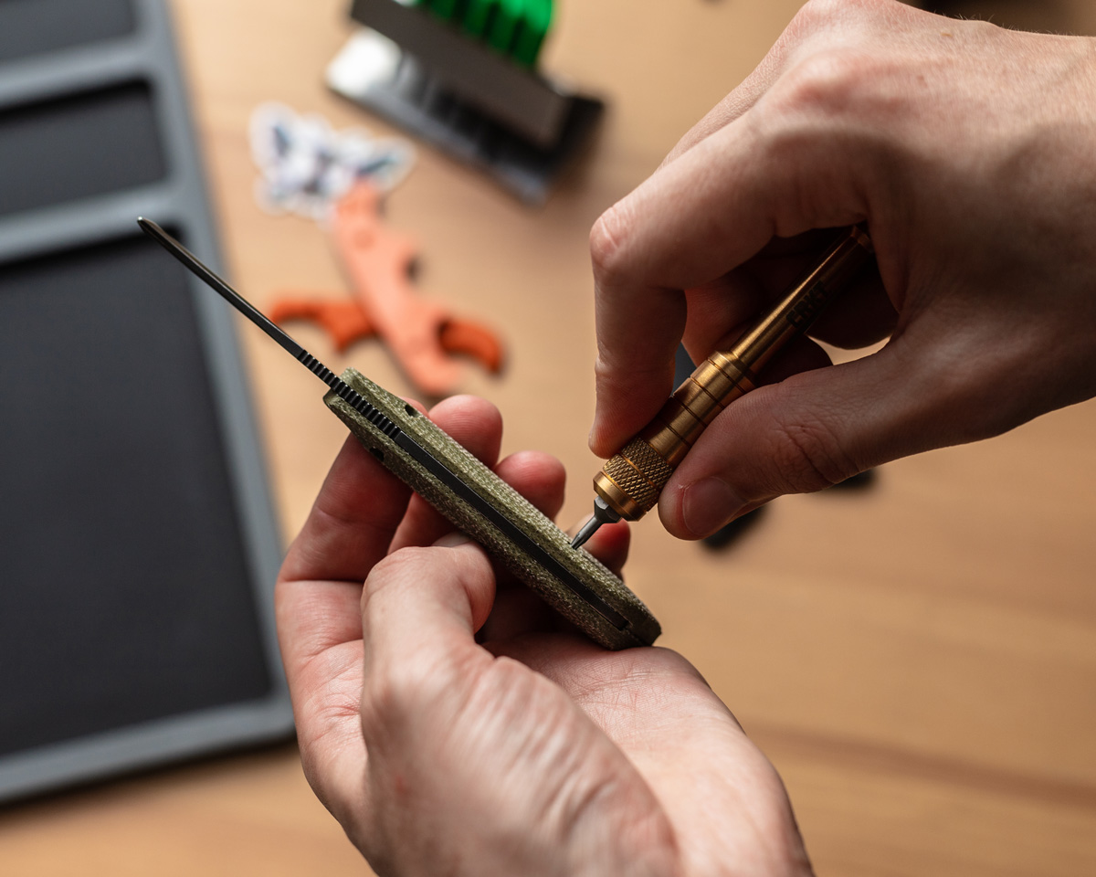 Tightening a screw on a knife handle with a brass mini screwdriver