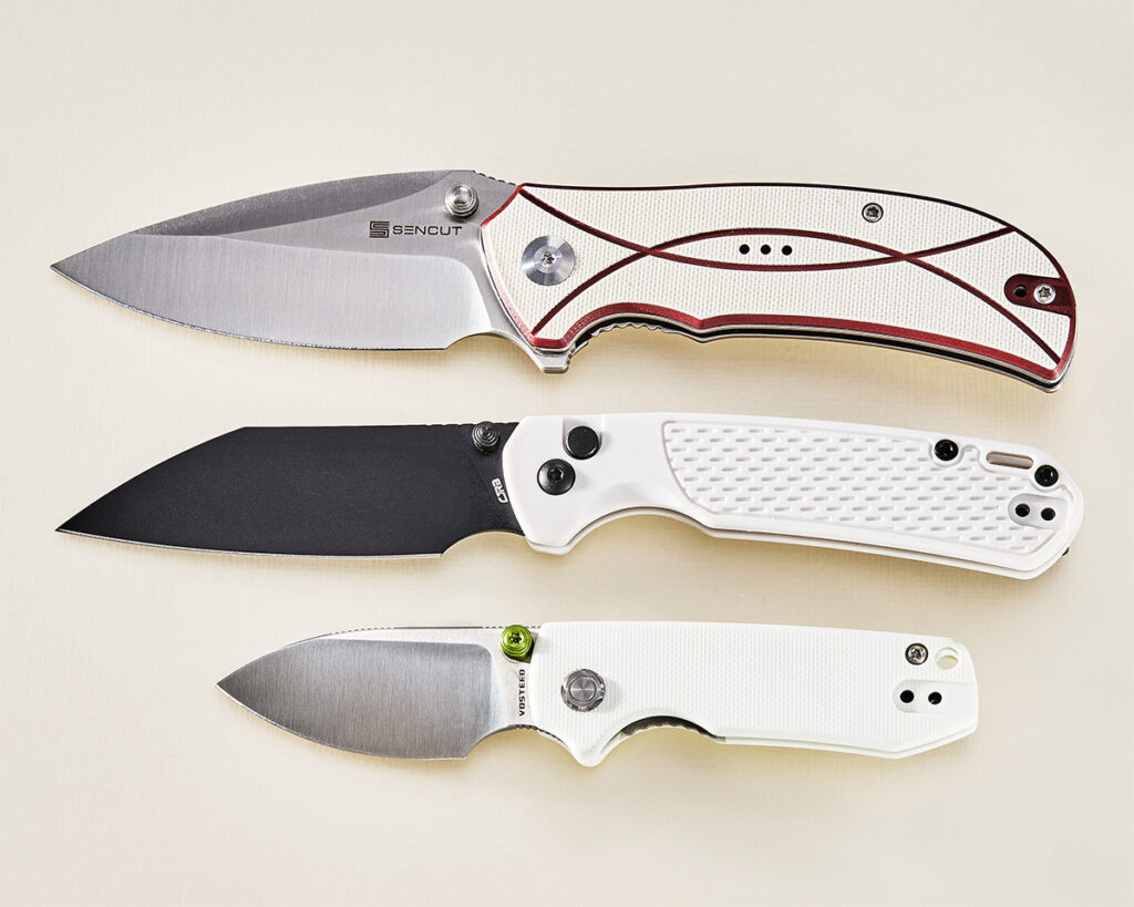 Three folding knives open on while background