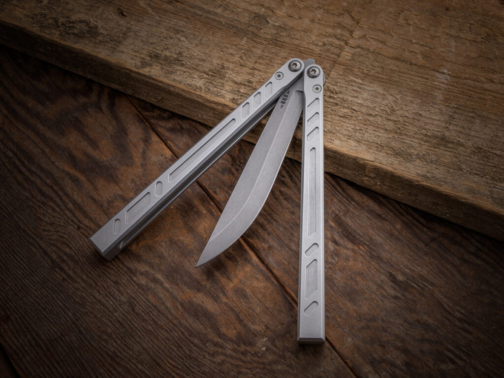 Balisong knife partially unfolded on wooden table