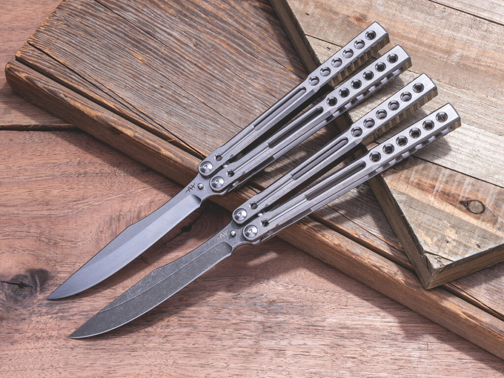 Two custom balisong knives open on wooden background