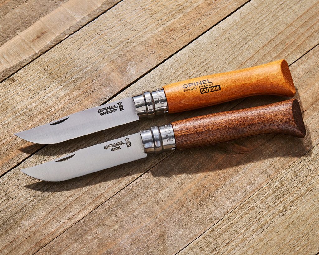Two Opinel No8 knives open on a wood surface